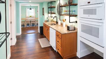 A kitchen with wooden cabinets, a countertop, a sink, a toaster, and a white oven.