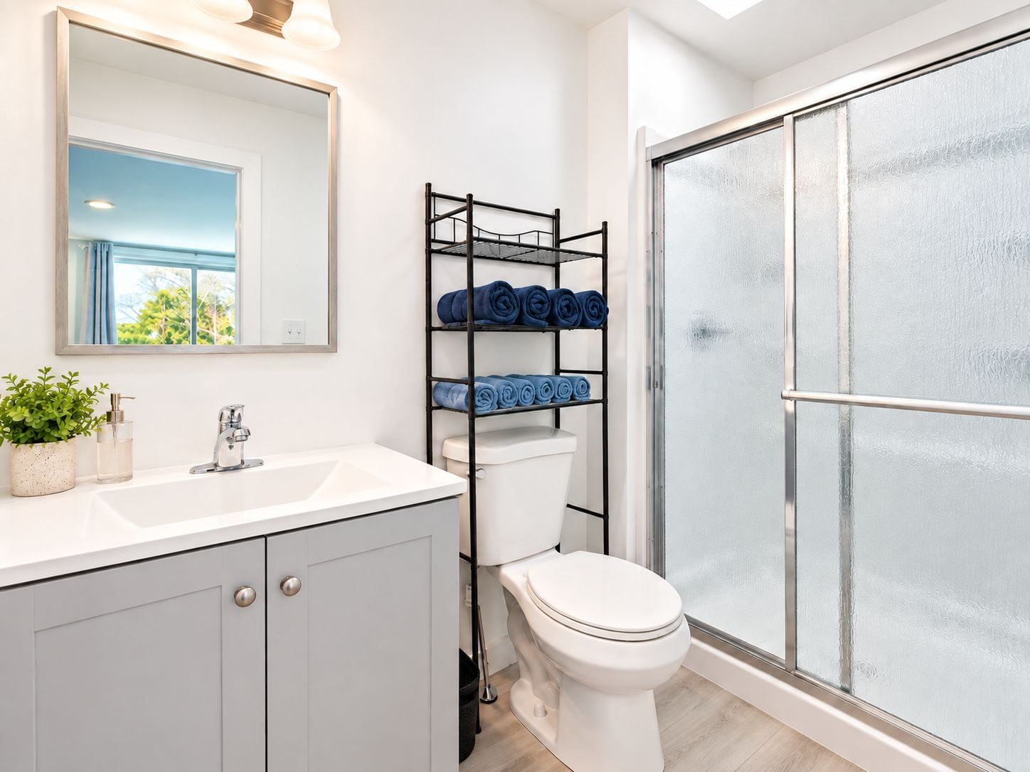 Un baño con un lavamanos blanco, un inodoro, un espejo y una cabina de ducha de vidrio.