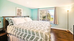 A bedroom with a bed, a window with curtains, a floor lamp, and a picture on the wall. - The Cottage Inn At Amos Lake (Preston)