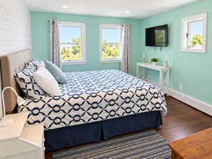 A bedroom with a bed, a bedside table, a TV, and two windows. - The Cottage Inn At Amos Lake (Preston)