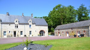 A stone building with a large entrance and a smaller attached structure. - Gîte 6 Personnes Chaleureux et au Calme à 15 Minutes des Plages du Débarquement (Picauville)