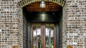 A brick building with a double door entrance, wooden steps, and a small porch area.