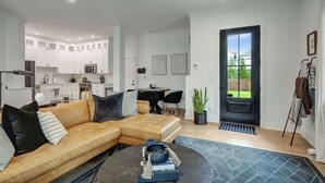 A modern living space with a sectional sofa, a dining area, and a kitchen.