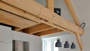 Una cuina moderna amb armaris blancs, taulell de fusta, forn integrat i llums penjants.