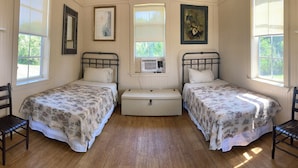 Una habitación con dos camas individuales, un aparador y una ventana con persianas.
