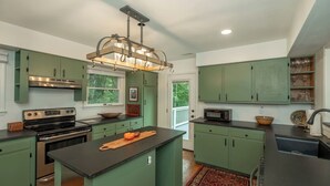A kitchen with green cabinets, a central island, a stove, and a microwave.