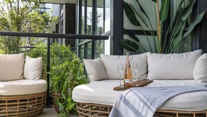 A balcony with wicker furniture, a bottle of wine, and a tray.