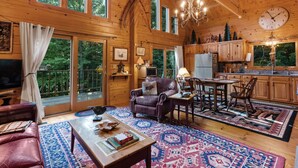 A spacious wooden cabin with a living room, dining area, and kitchen. - Lakefront Ski Log Cabin on 2 acres (Washington)