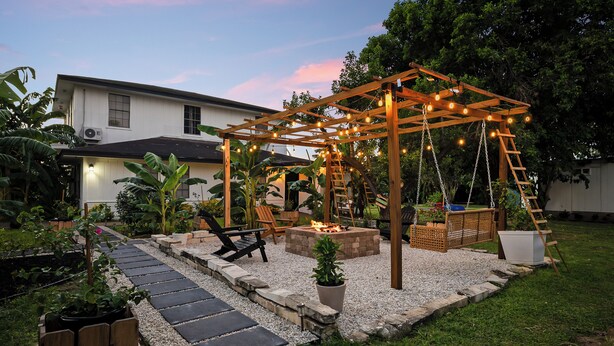 A backyard with a wooden pergola, fire pit, seating area, and a stone pathway. - Welcome to Casa Bugambilia  (Weslaco)