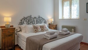 A bedroom with a bed, two bedside tables, a window with sheer curtains, and a radiator. - Swan Lake by Wonderful Italy (Bellagio)