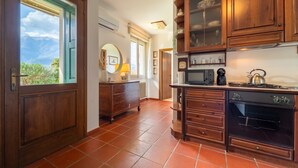 A kitchen with wooden cabinets, a stove, and a microwave. - Swan Lake by Wonderful Italy (Bellagio)