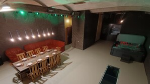 Een eetgedeelte met een bakstenen muur, een rode bank en een tafel voor zes personen.