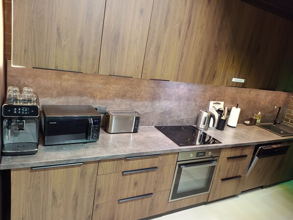 A modern kitchen with a built-in oven, a coffee machine, a toaster, and a sink.