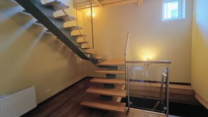 Een modern interieur met een houten trap, een klein raam en een radiator.