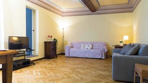 Een woonkamer met een televisie, twee banken, een houten kast en een lamp.