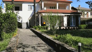 A two-story house with a tiled roof, a covered porch, and a stone pathway leading to the entrance.