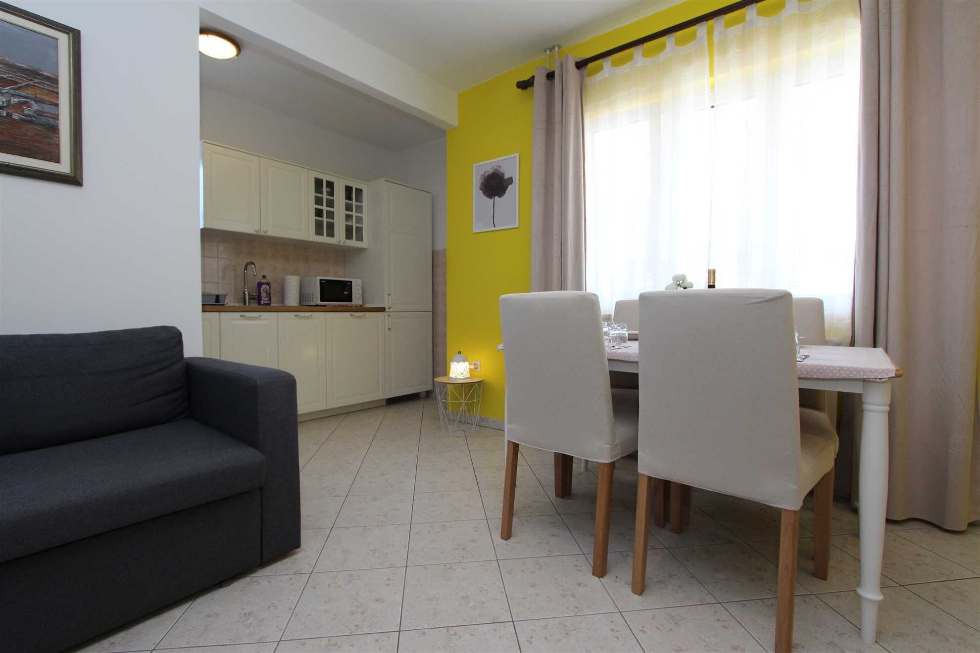 A compact living space with a dining area, kitchenette, and a sofa.