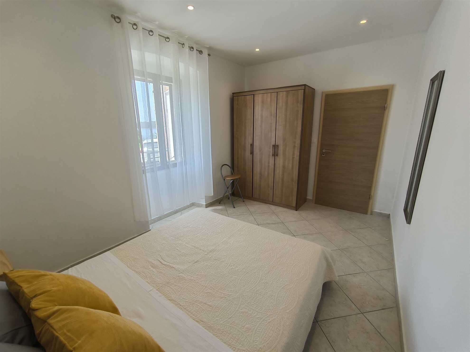 A bedroom with a bed, a wardrobe, a chair, and a door.