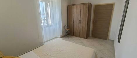 A bedroom with a bed, a wardrobe, a chair, and a door.