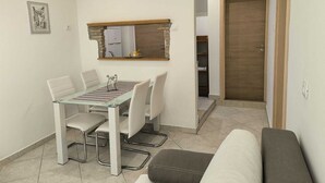 A compact living space with a dining area, kitchenette, and a door leading to another room. - MATIKA One-Bedroom Apartment with Terrace (Rovinj)