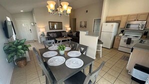 A modern kitchen with a dining area, featuring a central island, built-in appliances, and a chandelier.