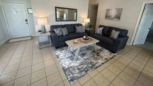 A living room with a dark-colored sofa set, a wooden coffee table, and a patterned rug.