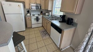 A compact kitchen with a refrigerator, microwave, stove, sink, and dishwasher.