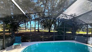 Ein überdachter Pool mit Blick auf Bäume und eine Rasenfläche.