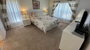 Un dormitorio con cama, mesitas de noche, un escritorio y una lámpara.