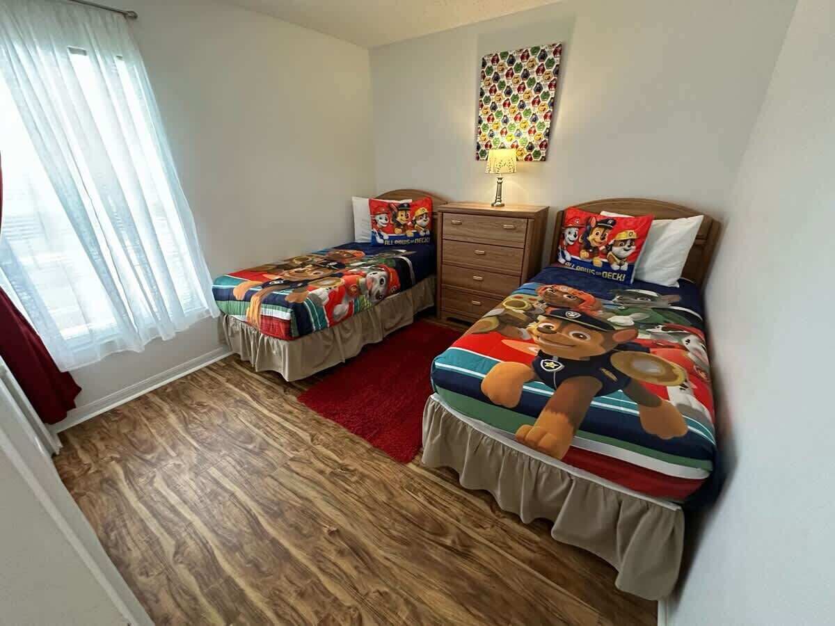 Ein Schlafzimmer mit zwei Betten, Holzboden, einem roten Teppich, einem Schminktisch und einer Wanddekoration.