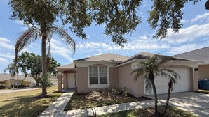 A residential house with a front yard, a driveway, and a garage. - Rebecca’s Villa (Haines City)