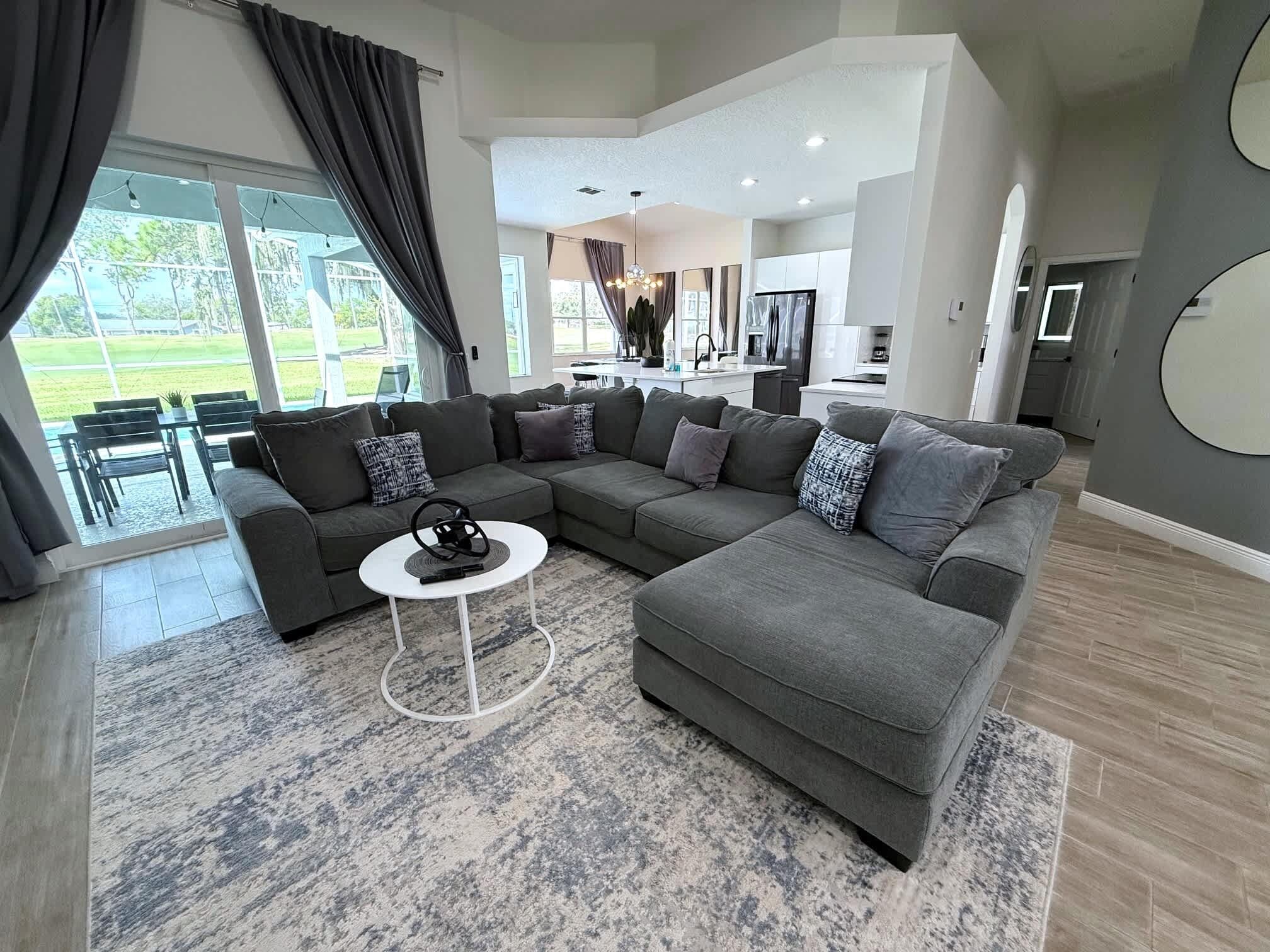 A modern living room with a sectional sofa, a coffee table, and a view of the outdoor patio.