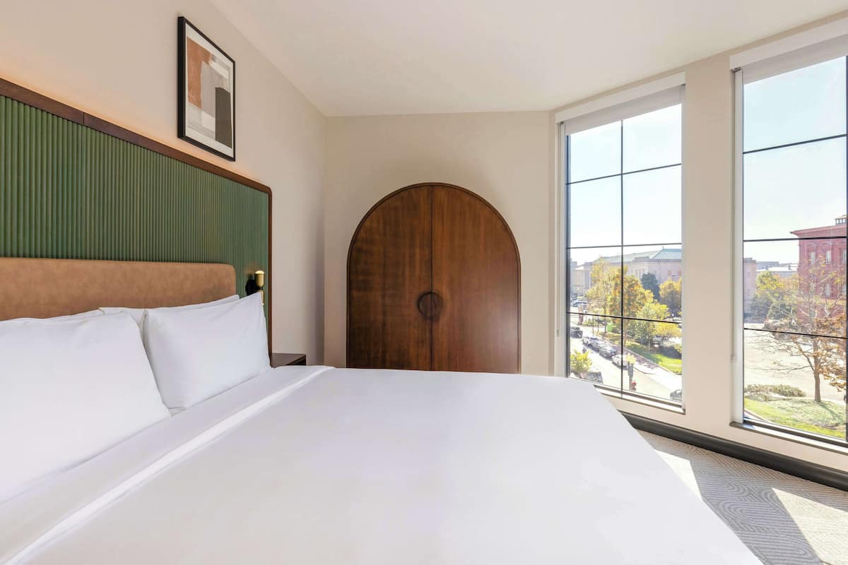 Una habitación de hotel con una cama grande, una puerta de madera y una ventana con vistas a la ciudad.