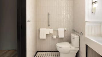 A modern bathroom with a toilet, a handrail, and a towel rack.