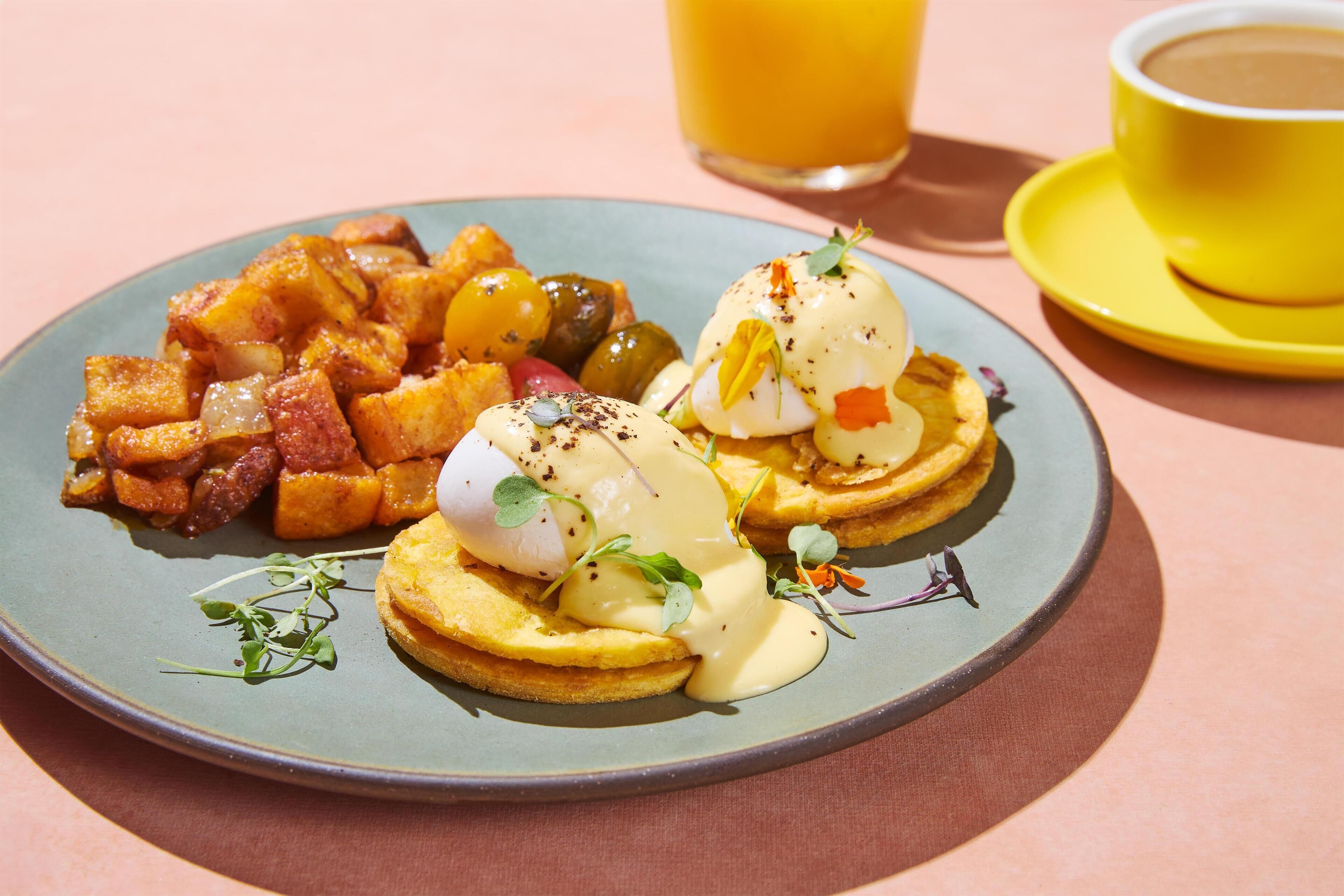 A plate of food with eggs benedict and hash browns.