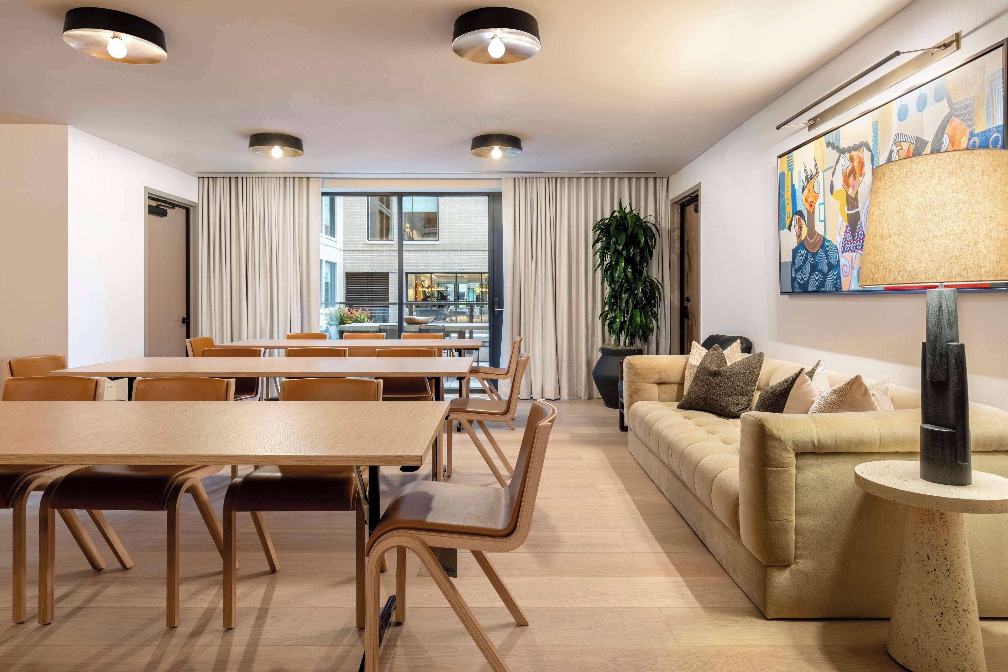 A modern living room with a sofa, coffee table, and dining area with chairs and a table.