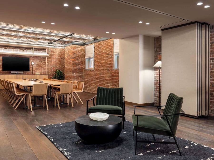 A modern conference room with a long table, chairs, and a black coffee table.