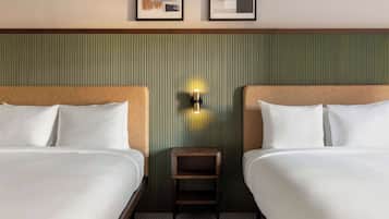 Ein Hotelzimmer mit zwei Betten, einem kleinen Nachttisch und einer wandmontierten Lampe.