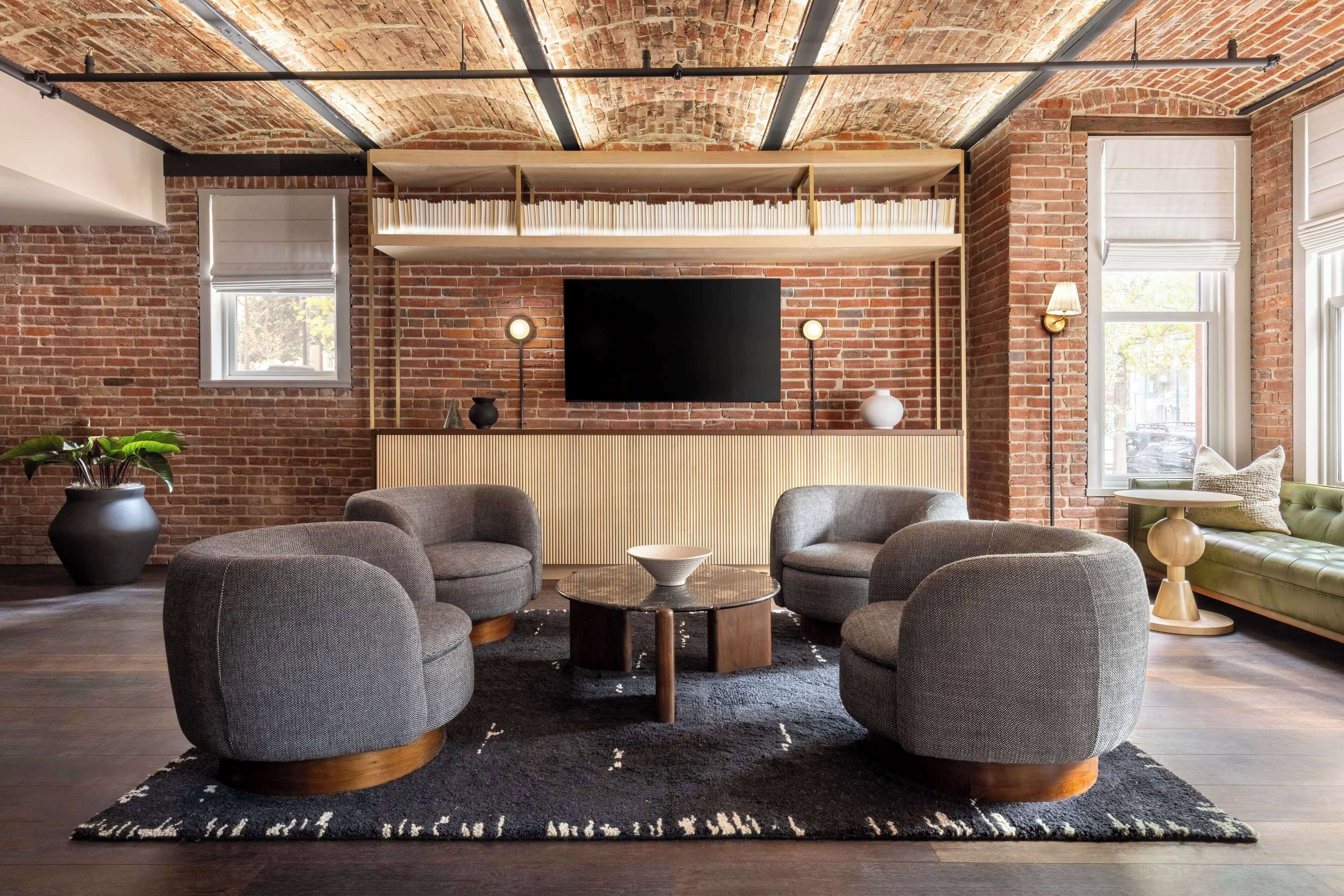 A modern living room with a brick wall, a flat-screen TV, and a green sofa.