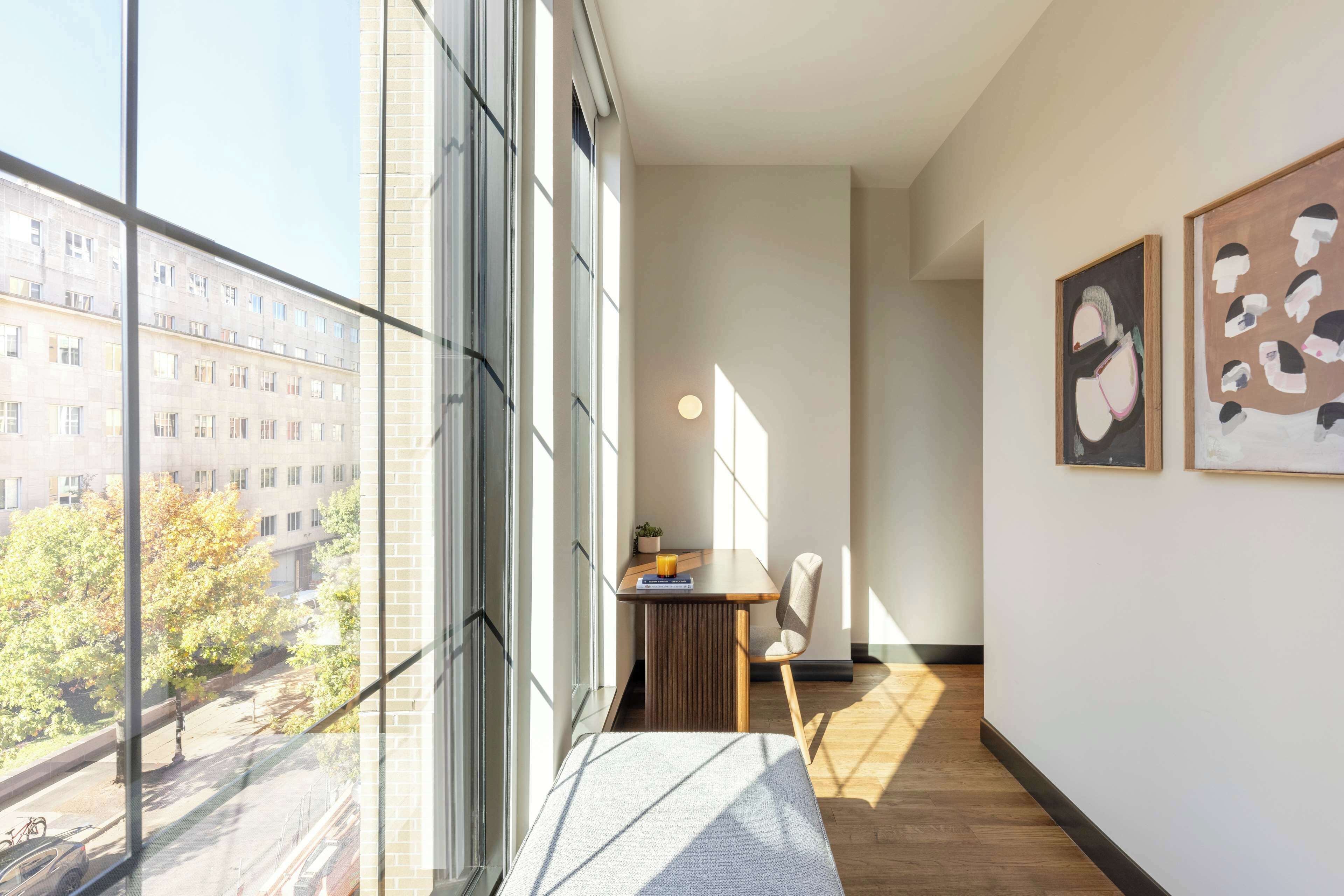 Ein modernes Interieur mit großen Fenstern, Holzboden und Kunstwerken an den Wänden.