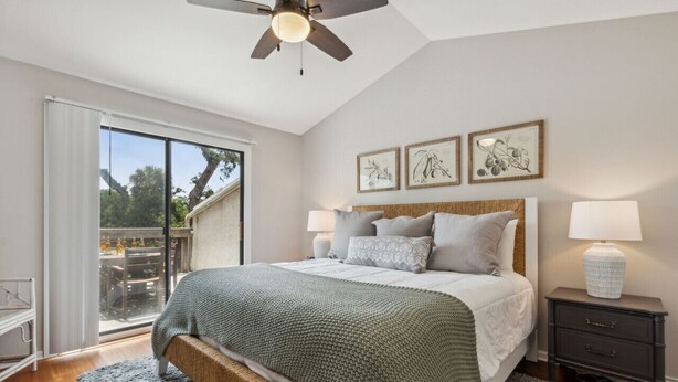 A bedroom with a bed, bedside tables, a ceiling fan, and a view through a sliding glass door. - 2625 Forest Ridge | Pool | Tennis/Pickleball | Large Deck (Fernandina Beach)