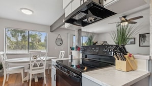 A modern kitchen with white cabinetry, a black stove, and a marble countertop. - 2625 Forest Ridge | Pool | Tennis/Pickleball | Large Deck (Fernandina Beach)