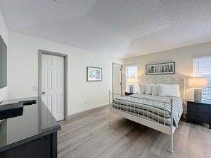A bedroom with a bed, bedside tables, a desk, and a door. - Eagle’s Nest Villa (Haines City)