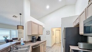 A modern kitchen with a stainless steel sink, a coffee maker, and a refrigerator. - Eagle’s Nest Villa (Haines City)