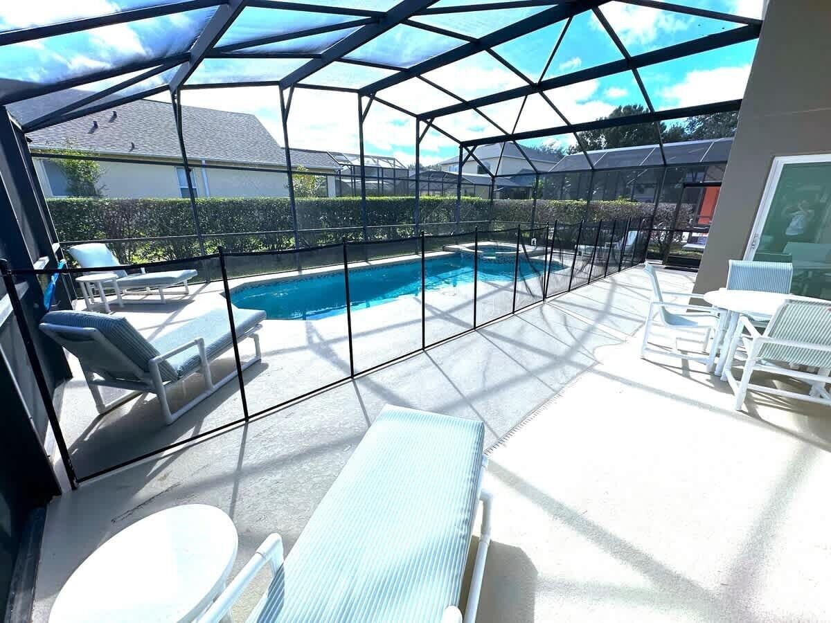 Un espace extérieur abrité avec une piscine, des chaises longues et une table.