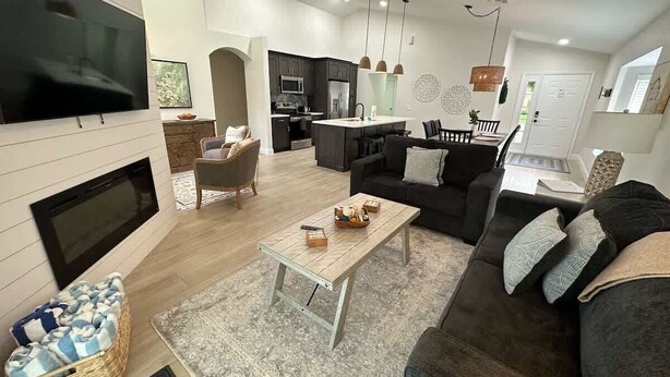 Ein modernes Wohnzimmer mit Flachbildfernseher, Kamin, Couchtisch und einer Couch.