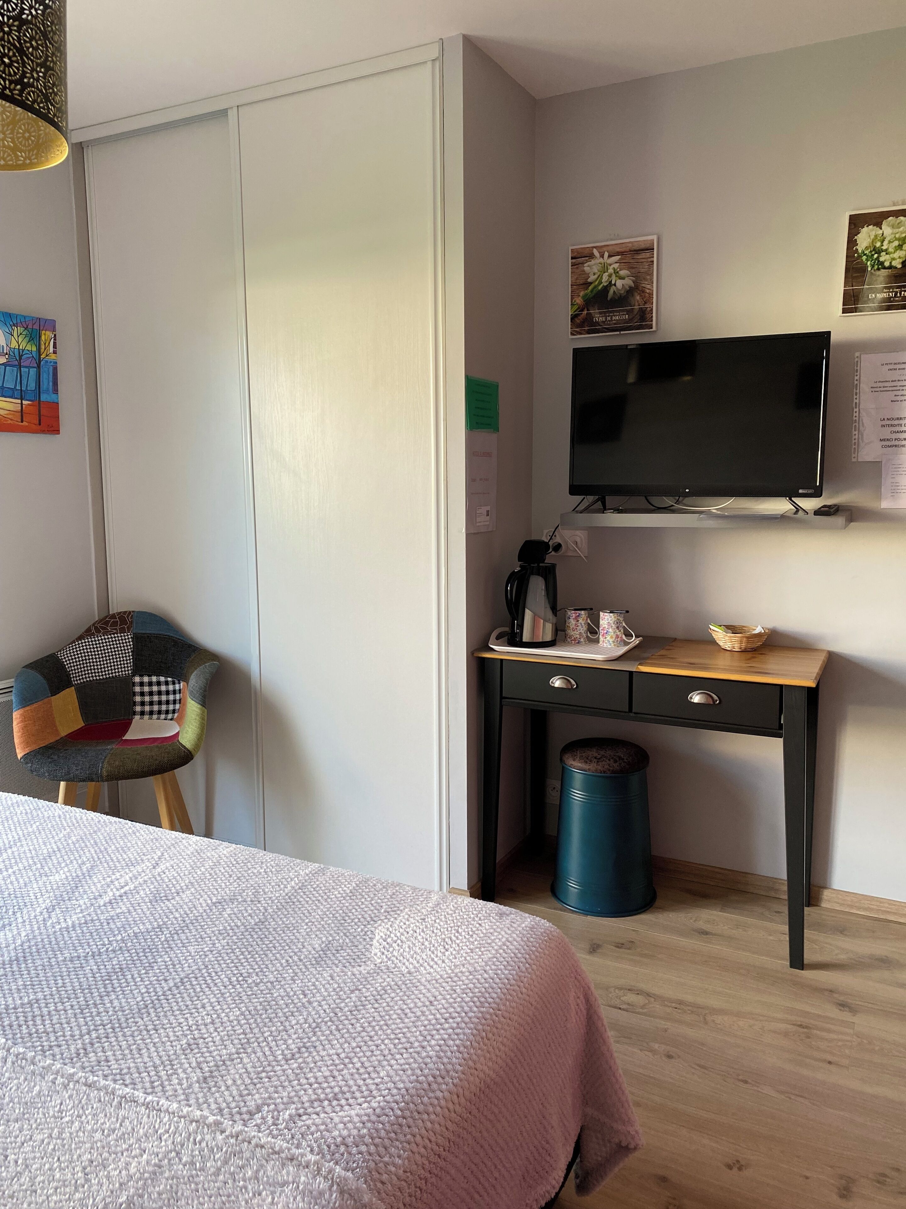 A bedroom with a bed, a desk with a computer, a chair, and a trash can.