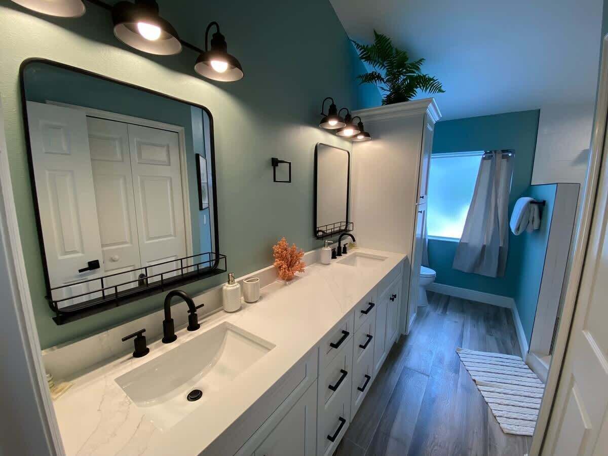 A modern bathroom with two sinks, a large mirror, and a shower area.