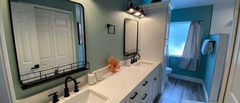 A modern bathroom with two sinks, a large mirror, and a shower area.