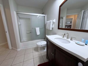 Une salle de bain moderne avec une douche à parois de verre, des toilettes blanches et un meuble-lavabo doté d’un grand miroir.